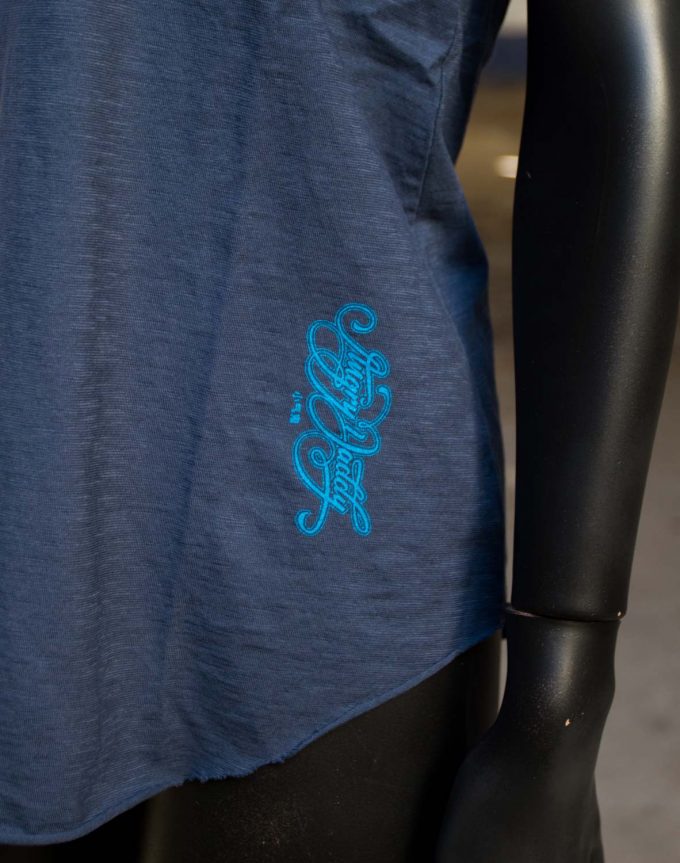 Detalle de camiseta azul de algodón orgánico, logotipo en el lateral máxima comodidad.