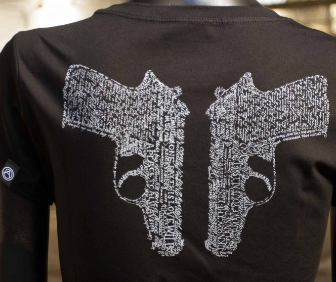 Trasera camiseta de algodón negra, con pistolas hechas a base de canciones de amor de la época del new wave, una mujer fuerte que nunca está desarmada.